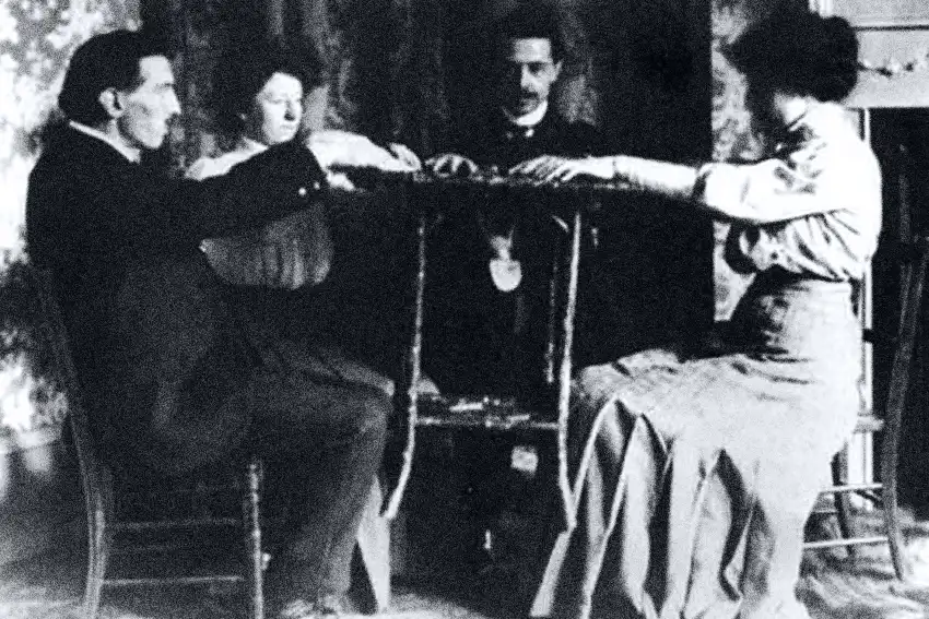 Médiuns com as mãos dadas em volta de uma mesa redonda