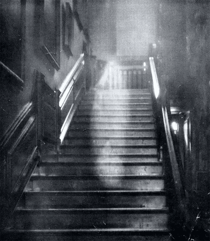 A famosa foto da Dama Marrom, uma figura translúcida e encapuzada descendo a escadaria principal de Raynham Hall.