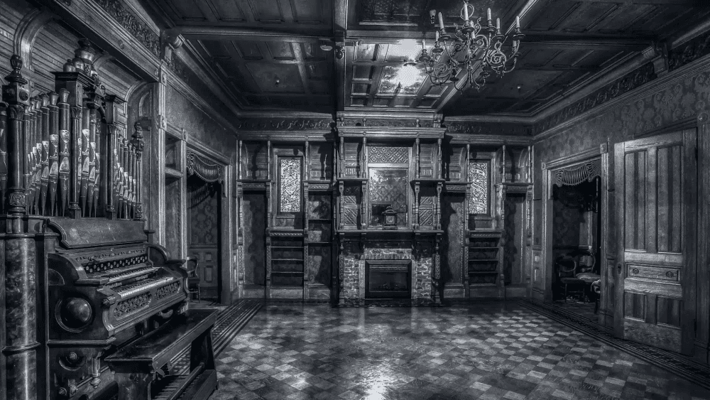 Interior Winchester: Sala luxuosa com órgão de tubos, vitrais e lareira na Mansão Winchester. Atmosfera de opulência e mistério arquitetônico.