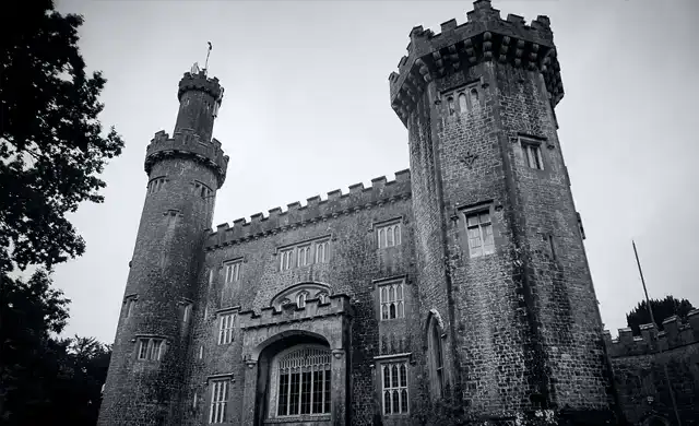 Imponente torre de pedra na Irlanda sob céu nublado. Imagem em preto e branco que ressalta a solidez e o aspecto sombrio da fortaleza.