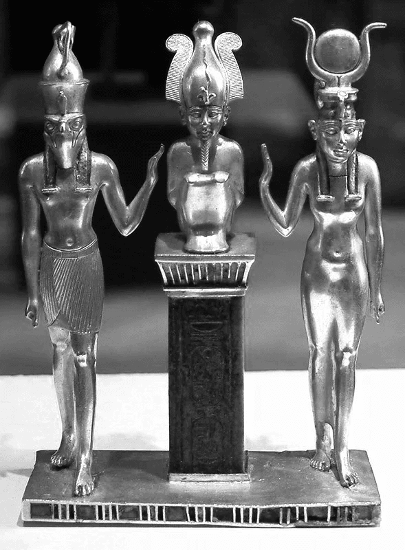 Tríade de Osorkon II em metal nobre. Osíris sobre um pilar central é flanqueado pelas figuras protetoras de Ísis e Hórus, em uma representação sagrada de linhagem divina.