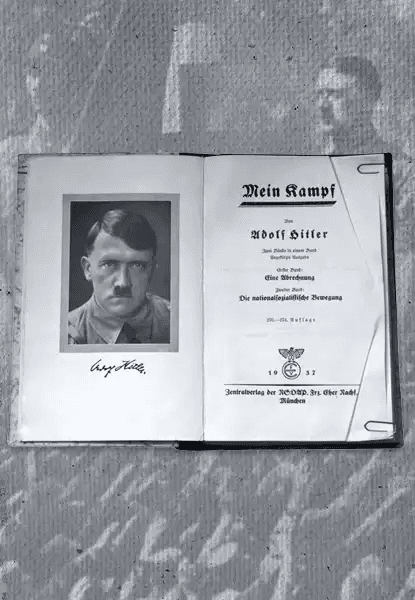 Fotografia em preto e branco de uma cópia aberta do livro Mein Kampf, de Adolf Hitler. À esquerda, página com retrato fotográfico do autor e sua assinatura manuscrita abaixo. À direita, página de título com texto em alemão: Mein Kampf por Adolf Hitler, indicando volumes I e II, editora Franz Eher Nachfolger, Munique, 1932. No centro inferior da página de título, há o símbolo da suástica dentro de um círculo. O livro está sobre uma superfície texturizada, possivelmente tecido ou papel envelhecido.