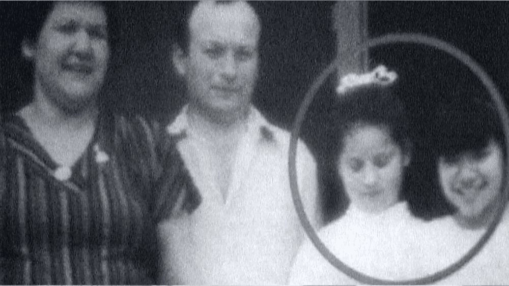 Foto antiga e granulada em preto e branco. Um casal posa com duas filhas pequenas; um círculo destaca as meninas, antecipando o trágico destino da família.