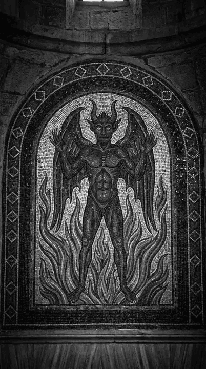 Mosaico antigo em preto e branco dentro de um arco de pedra, retratando uma figura demoníaca alada e com chifres. O ser está com as mãos erguidas, cercado por chamas estilizadas