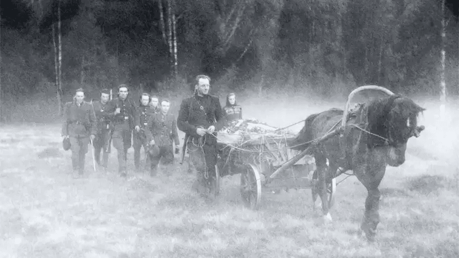 Soldados conduzem uma carroça fúnebre por uma floresta nebulosa. A névoa densa e os uniformes antigos criam uma atmosfera melancólica de guerra e despedida.