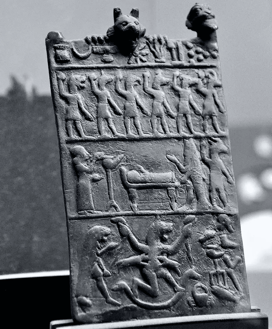 Placa de relevo mesopotâmica com figuras rituais e deidades zoomórficas ao redor de um leito. A pedra esculpida narra um rito milenar de passagem ou proteção espiritual.