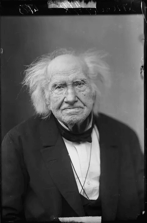 Michel Eugène Chevreul idoso usando um terno e olhando fixamente para câmera em polaroid de 1886