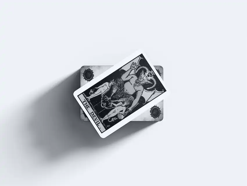 Carta de tarot O Diabo sobreposta a um baralho. A figura mítica com chifres é retratada em uma ilustração clássica e sombria.